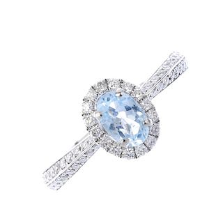 An aquamarine and diamond dress ring. The oval-shape aquamarine, within a brilliant-cut diamond surr