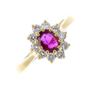An 18ct gold ruby and diamond cluster ring. The oval-shape ruby, within a brilliant-cut diamond surr