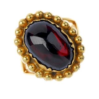 A garnet single-stone ring. The oval garnet cabochon, within a beaded surround, to the bifurcated sh