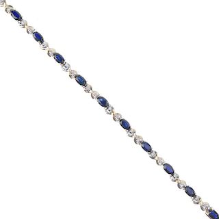 A 9ct gold sapphire and diamond line bracelet. Designed as a series of oval-shape sapphires, with si