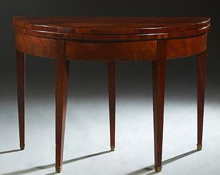 French Louis XVI Style Carved Mahogany Demilune Games Table, early 20th c., the figured top opening to a gilt tooled baize lined playing surface, over