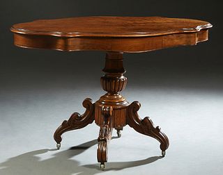 French Carved Walnut Center Table, c. 1870, the stepped tortoise top with two side drawers, on a reeded urn support to four splayed scrolled legs on c