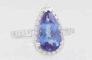 Lady's 18K White Gold Dinner Ring, with a 2.97 ct. pear shaped tanzanite atop a conforming border of round diamonds, the shoulders of the band also mo