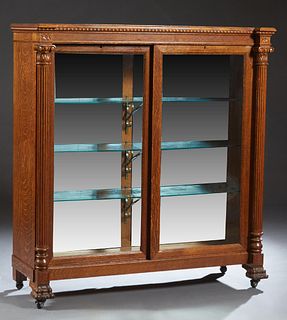 American Carved Tiger Oak Bookcase, c. 1900, the stepped breakfront top over setback double glazed sliding doors, flanked by engaged reeded Ionic colu