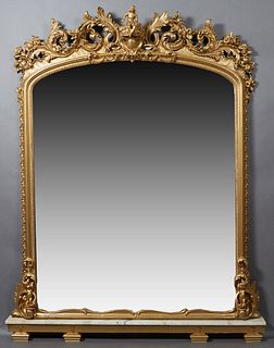 American Gilt and Gesso Rococo Revival Figural Overmantel Mirror, 19th c., the arched top with an elaborate central seated putto and scrolled leaf and
