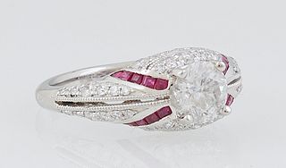 Lady's Platinum Dinner Ring, with a central 1.01 carat round diamond, above diamond paneled sides, flanked by diagonal lines of baguette rubies, flank
