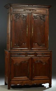 French Louis XV Style Carved Oak Buffet a Deux Corps, early 19th c., the leaf carved ogee crown over double fielded panel cupboard doors with brass fi