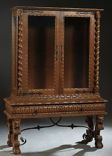 French Henri II Style Carved Oak Vitrine, c. 1880, the carved sloping crown over setback double wide beveled glazed doors, with iron strap hinges and 