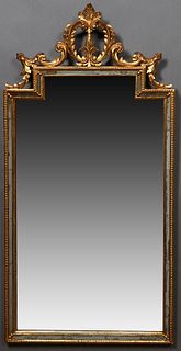 Florentine Gilt and Gesso Cushion Mirror, 19th c., with a pierced circular leaf and scroll surmount, over an architectural mirror plate flanked by nar
