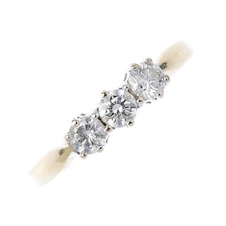 An 18ct gold diamond three-stone ring. The brilliant-cut diamond, with similarly-cut diamond sides,