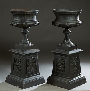 Pair of Cast Aluminum Urns on Stands, 20th/21st c., the everted rim over baluster floral relief sides, on a tapered socle support, to an integral squa
