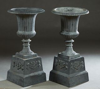 Pair of Cast Iron Campana Form Jardinieres, 20th/21st c., the everted relief decorated rims over reeded sides and a socle support, on a square stepped