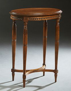 French Louis XVI Style Carved Walnut Lamp Table, 20th c., the stepped oval top over a carved skirt, on tapered cylindrical legs joined by two U-shaped