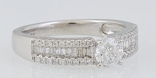 Lady's Platinum Dinner Ring, with a central .4 ct. round diamond flanked by shoulders of the band with a central row of diamond baguettes, within bord