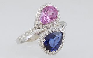 Lady's 18K White Gold Dinner Ring, of bypass form, each end with a pear cut natural sapphire, one blue, one pink, within diamond mounted borders, the 