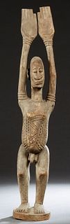 African Dogon Carved Wood Male Figure, 20th c., of a man holding up both arms, on an integral oval plinth, H.- 42 in., W.- 7 1/2 in., D.- 6 1/2 in.