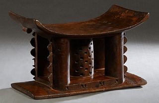 Ashanti Carved Wood Chief's Stool, c. 1930, the curved seat on four columnar supports around a central pierced cylindrical support, on an integral inc