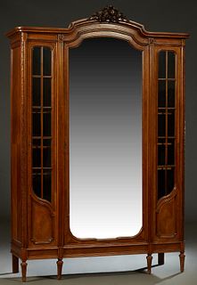 French Louis XVI Style Carved Mahogany Three Door Armoire, early 20th c., the stepped arched crown with a central leaf and nut crest, over an arched w