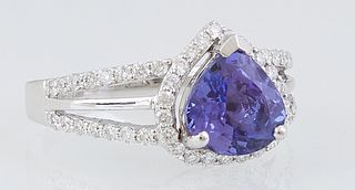 Lady's 18K White Gold Dinner Ring, with a trillion cut 2.04 tanzanite, atop a conforming border of tiny round diamonds, the split shoulders of the ban