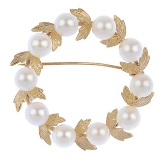 A 9ct gold cultured pearl wreath brooch. Designed as a cultured pearl circle, with textured leaf acc
