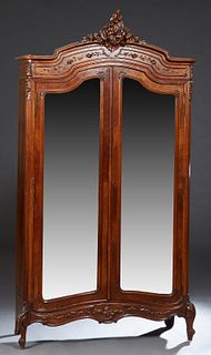 French Louis XV Style Carved Mahogany Armoire, early 20th c., the arched crown with an elaborate scroll and nut surmount, above double arched wide bev