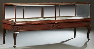 American Carved Mahogany Store DIsplay Case, early 20th c., with a glass top, front and sides and sliding mirror doors at the rear, on a plinth base w