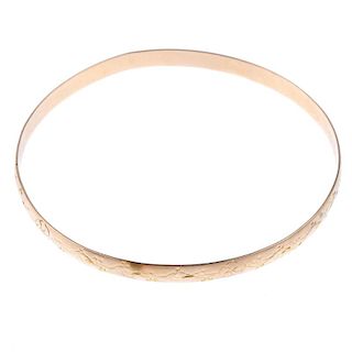 Three slave bangles. To include two 9ct gold textured bangles, together with a floral engraved bangl
