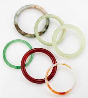 A GROUP OF FIVE JADE AND OTHER HARDSTONE BANGLES AND A GREE