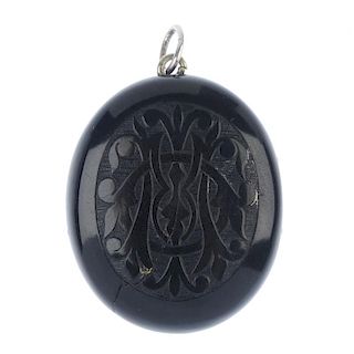 A late Victorian jet locket. Of oval-shape outline, the front carved to depict a monogram, opening t