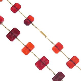 An intaglio necklace. The rectangular carnelian panels each engraved to one side with a flower, some