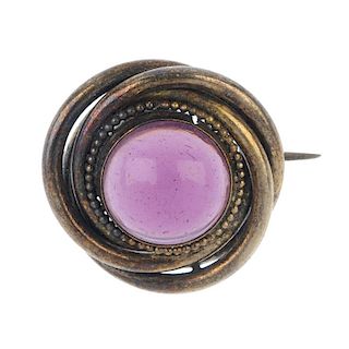 A late 19th century paste brooch. The circular purple paste cabochon, within a stylised knot surroun