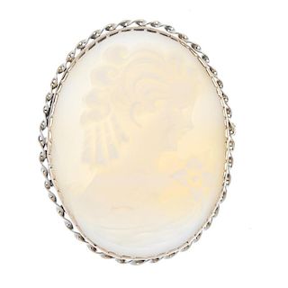 A cameo brooch. The light coloured shell carved to depict the portrait of a lady, to the twisting su