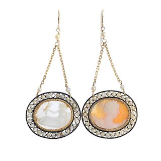 Two shell cameo ear pendants. Each designed as an oval-shape shell cameo, within a seed pearl and bl