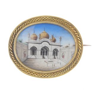A cameo brooch. The oval painted panel beneath the glazed panel depicting an Indian building with do