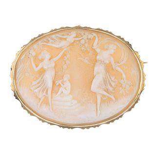 A cameo brooch. Of oval outline, the shell depicting three dancing graces and a putto playing a pipe