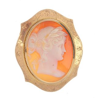 An 18ct gold cameo brooch. The oval carving depicting a lady in profile to the scalloped engraved bo