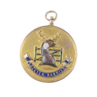 An early 20th century gold enamel medallion. Of circular outline with enamel stag head, gate and scr