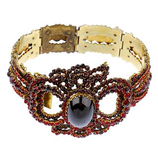 A garnet and paste bracelet. The oval garnet cabochon, within a circular-shape red paste and garnet