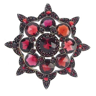 <p>A garnet and red paste brooch. Of tiered design with a shaped outline and set with faceted garnet