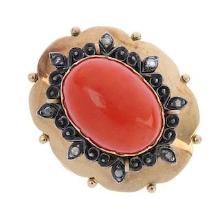 An early 20th century gold coral and diamond ring. The oval coral cabochon, within a petal and scrol