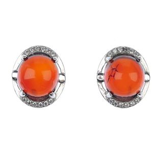 A pair of natural Burmese blood amber ear studs. The orange-brown oval amber cabochons measuring 0.9