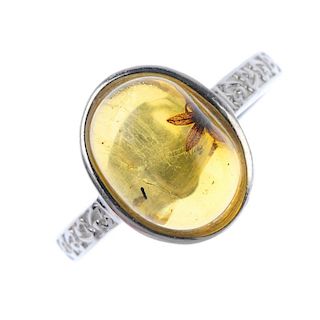 A natural Burmese amber ring with floral inclusion. The oval cabochon measuring 1.2cms, with small p