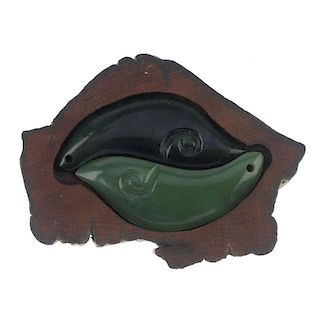 Two New Zealand jade ying yang pendants with carved koru in wooden display panel. One pendant carved
