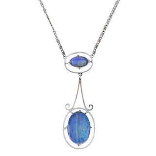 An opal pendant. Designed as an oval opal cabochon, within a halo surround, to the scrolling link, s