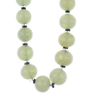A green gem necklace. Designed as slightly graduated spherical beads with faceted black and colourle
