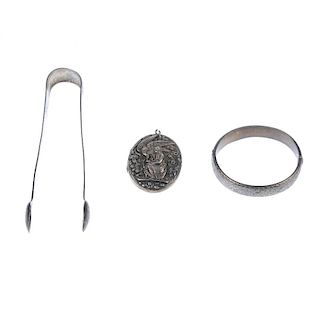Three items of jewellery and novelties. To include a silver locket depicting Hebe administering nect
