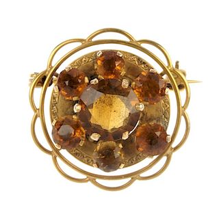 A citrine cluster brooch. The circular-shape citrine, within a similarly-cut citrine and engraved su