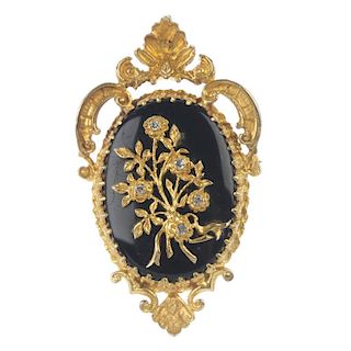 A 9ct gold onyx and diamond pendant. The main oval onyx panel with overlaid floral design, each flow