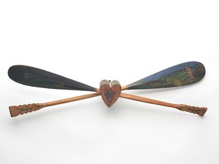 Two decorative canoe paddles with scenes painted on them, crossed in a heart that is 2.5" thick.