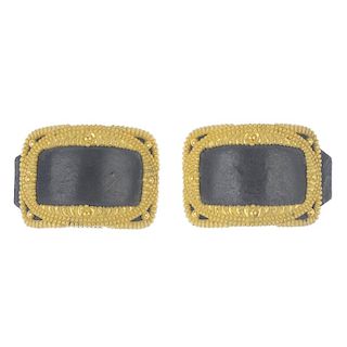 Two shoe buckles. Both designed as open gold-tone rectangles with textured detailing and black leath
